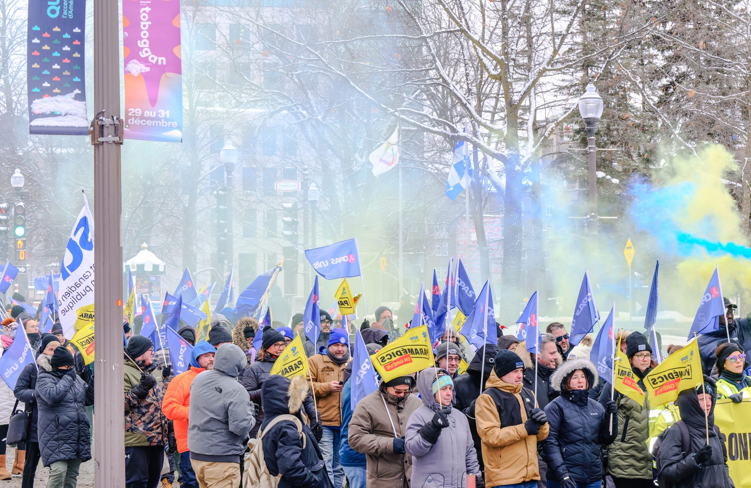 Manifestation de paramédics et de leurs alliés, brandissant des drapeaux syndicaux dans les rues de Québec en plein hiver.